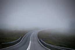 A winding road that leads into a patch of fog