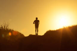Sihouette of a person running with the sun setting
